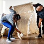 Couple moving a piece of wooden furniture