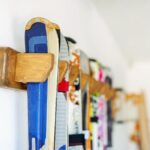 Skis in a variety of colors hang on a wall in a wooden holder.