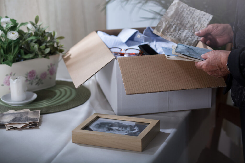 A person packs away photographs and letters into a cardboard box