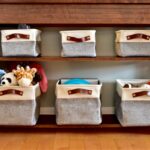 Fabric baskets filled with toys sit on the shelves of a wooden table.