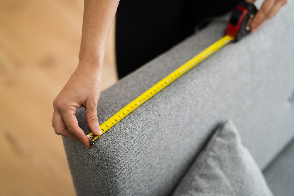 Person measuring edge of a couch.