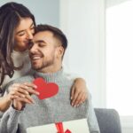 A man and woman embracing as they open Valentine’s Day gifts from each other.