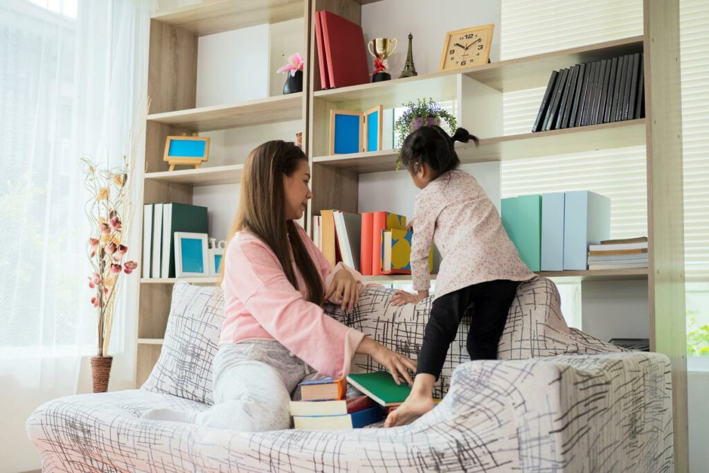 Mother and daughter helping each other organize the living room in their small apartment.